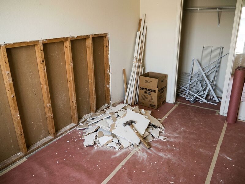 Non-load-bearing drywall removed to the studs with baseboard stacked